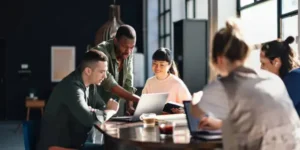 Gestão de Carreira Young professionals or students collaborating in a bright, contemporary co-working environment, displaying teamwork and productivity.